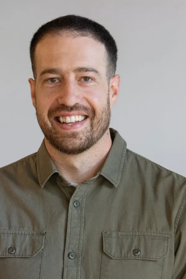 Luca Borra lächelt in die Kamera vor neutralem Hintergrund.